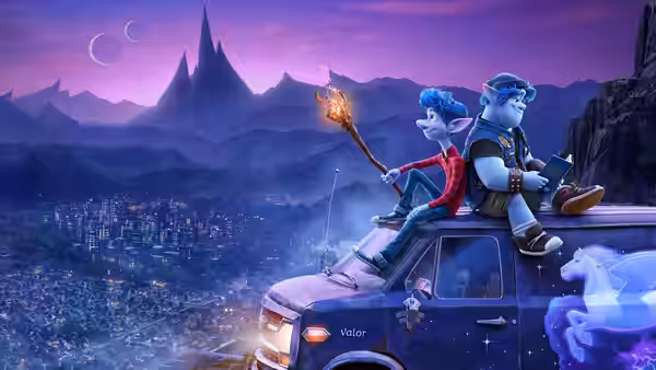 Ian and Barley sit atop their van overlooking a city and distant mountains
