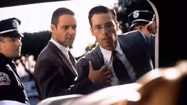 two suited men and a police officer look intently at something off camera