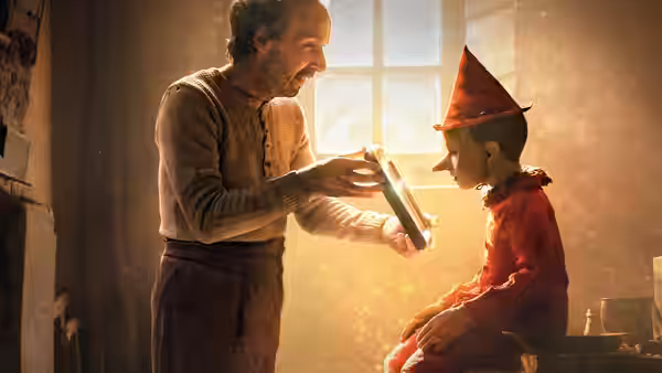 Mister Geppetto presents a book to Pinocchio in a warmly lit room