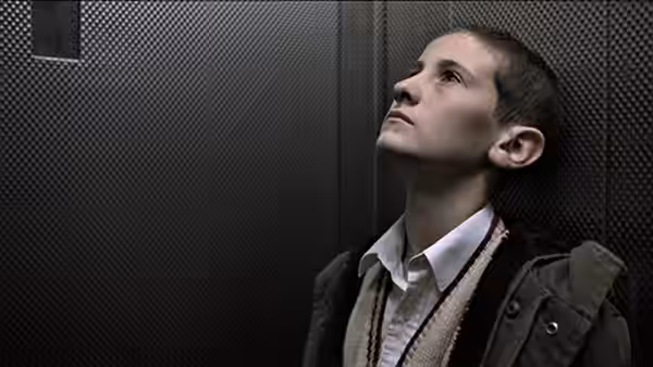 James (William Eadie) leans against the wall inside an elevator