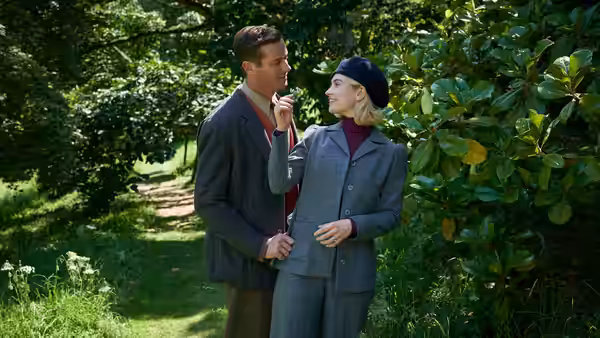 Mrs. de Winter (Lily James) and Maxim (Armie Hammer) talk in a leafy garden