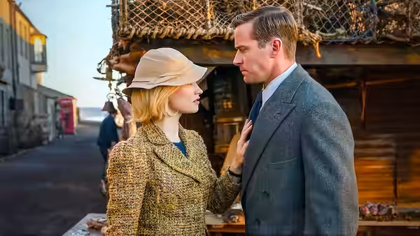 Mrs. de Winter (Lily James) rests a hand on Maxim (Armie Hammer) at the harbor