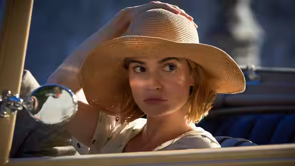 Mrs. de Winter (Lily James) adjusts her sunhat in a convertible