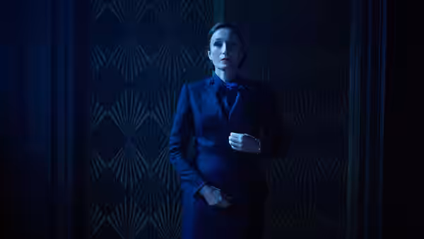 Mrs. Danvers (Kristin Scott Thomas) stands alone in a dimly lit hallway