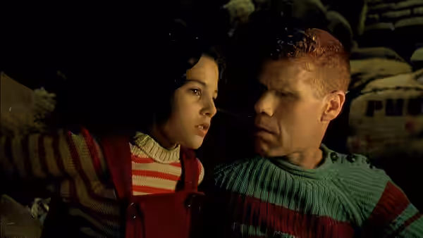 Miette (Judith Vittet) and One (Ron Perlman) face each other in a dim storeroom