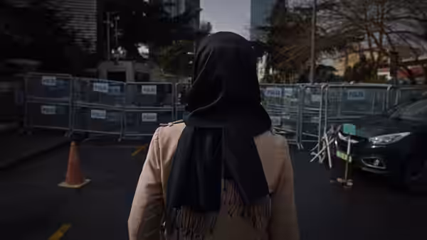 A woman in a black headscarf approaches a police barricade outside a building