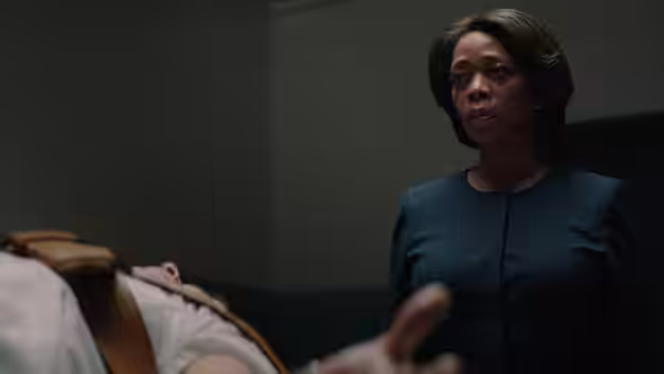 Warden Bernadine Williams (Alfre Woodard) stands beside a person lying on a bed