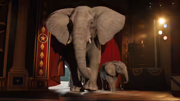An adult elephant and a calf stand backstage beneath circus lights