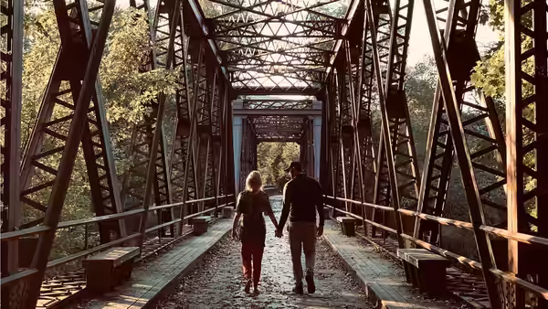 Evelyn Abbott (Emily Blunt) and Lee Abbott (John Krasinski) walk across a steel truss bridge