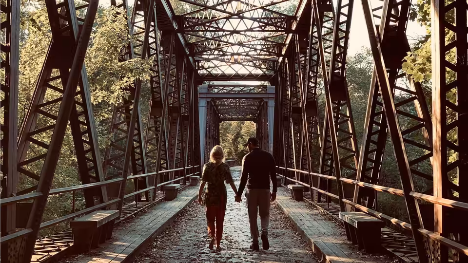 Evelyn Abbott (Emily Blunt) and Lee Abbott (John Krasinski) walk across a steel truss bridge