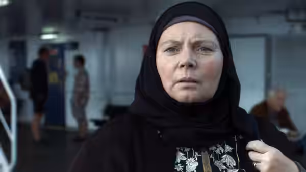 Mary (Joanna Scanlan) stands aboard a ferry, clutching her bag