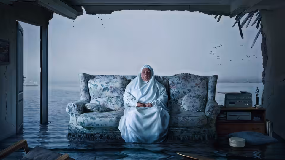 Mary (Joanna Scanlan) sits on a sofa in her flooded living room