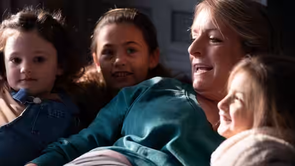 Ava (Claire Rushbrook) reclines with three children gathered close around her
