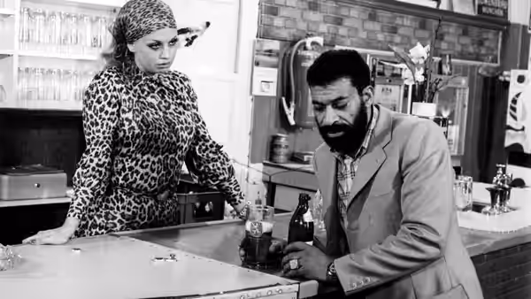 Ali (El Hedi ben Salem) leans on a bar while a woman in a patterned dress watches