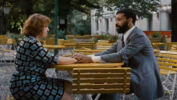 Emmi Kurowski (Brigitte Mira) and Ali (El Hedi ben Salem) hold hands across a café table outdoors