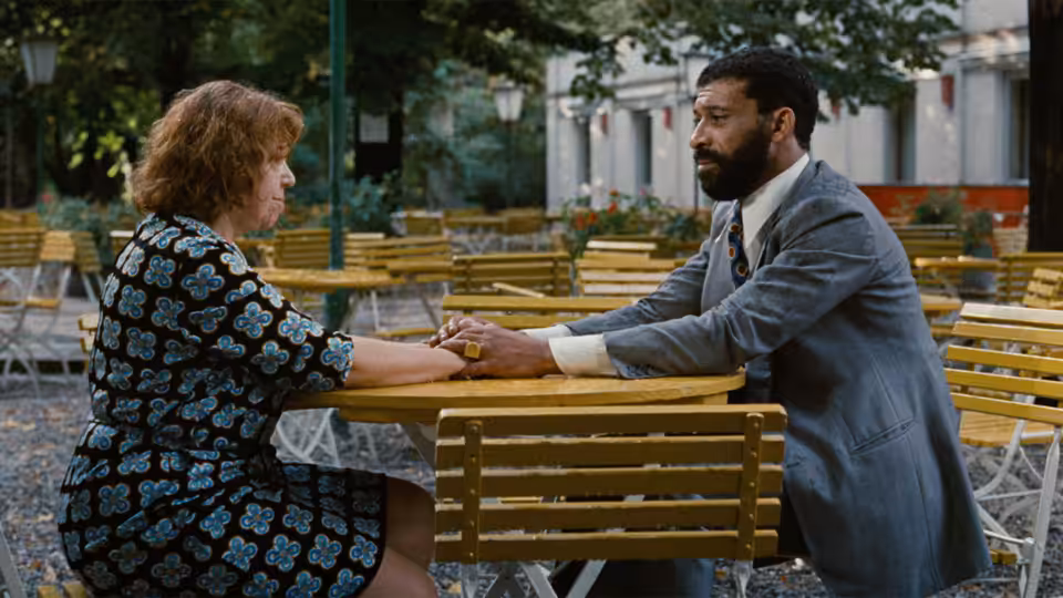 Emmi Kurowski (Brigitte Mira) and Ali (El Hedi ben Salem) hold hands across a café table outdoors