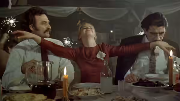 a woman in a red dress with arms outstretched at a dinner table