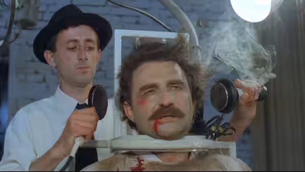 a man strapped in a chair with wires while another holds electrical devices