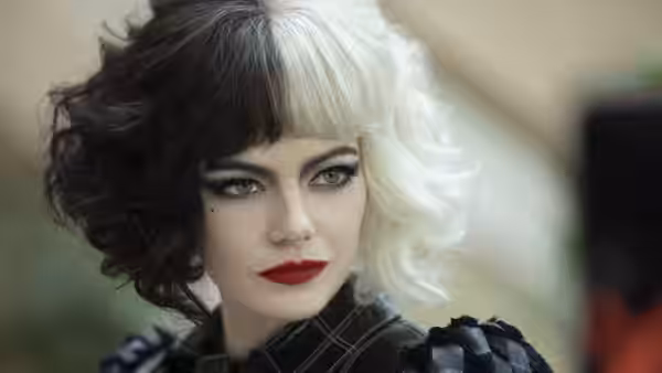 Cruella (Emma Stone) looks ahead beneath her distinctive half-black, half-white hair