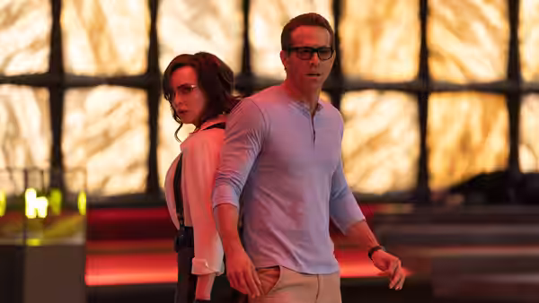 Millie (Jodie Comer) and Guy (Ryan Reynolds) stand back to back in a glowing room