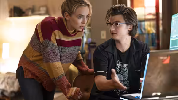 Millie (Jodie Comer) leans over as Keys (Joe Keery) gestures beside a computer