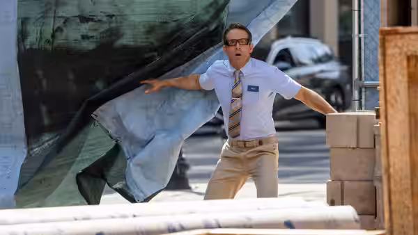 Guy (Ryan Reynolds) stands with arms spread as a large sheet billows behind him on a sidewalk