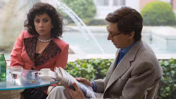 Patrizia Reggiani (Lady Gaga) sits beside Maurizio Gucci (Adam Driver) as he reads outdoors