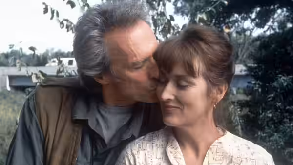 Robert Kincaid (Clint Eastwood) kisses Francesca Johnson (Meryl Streep) on the forehead outdoors