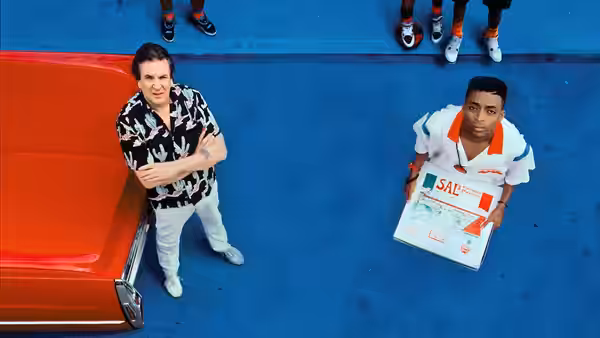 Sal (Danny Aiello) stands by his red car while Mookie (Spike Lee) holds a pizza box