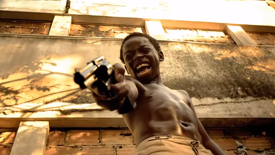 Shirtless boy pointing a pistol upwards while shouting