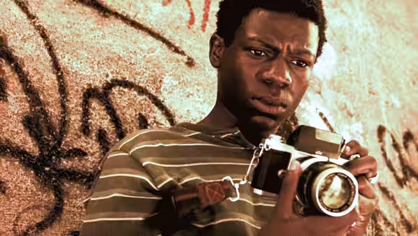 Young man holding a camera against a graffiti wall