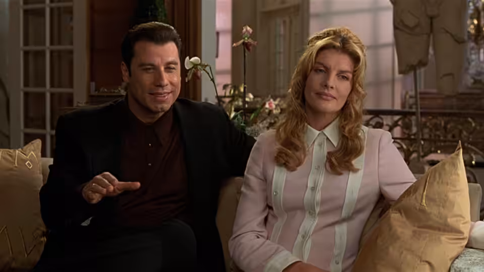 Chili Palmer (John Travolta) sits with Karen Flores (Rene Russo) on a couch