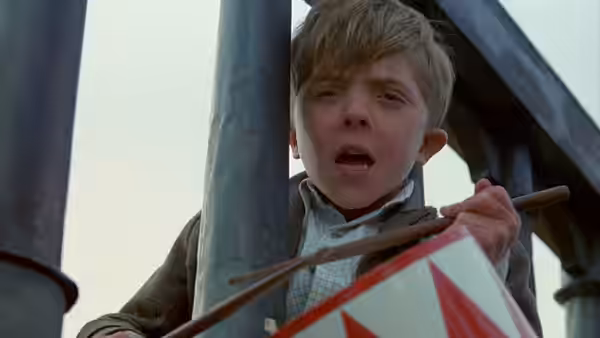 Oskar Matzerath (David Bennent) beats his drum between the dark supports of a tower