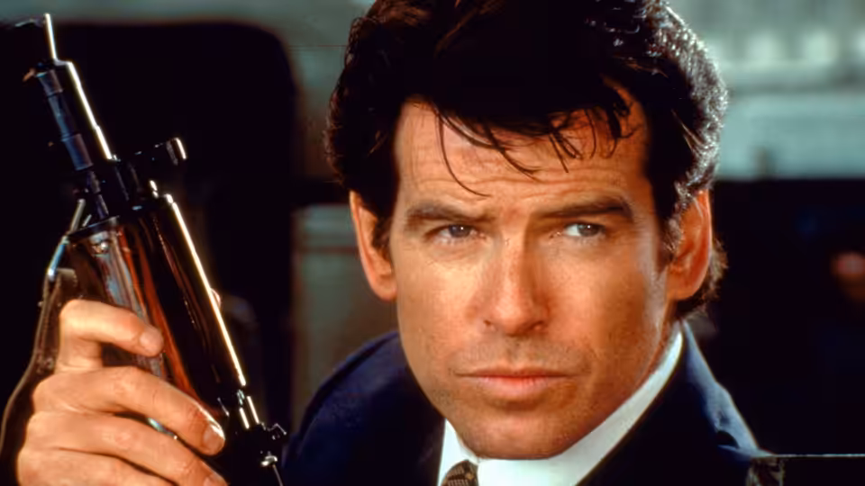 James Bond (Pierce Brosnan) holding a submachine gun and looking sideways