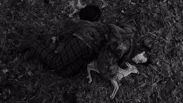 William Blake lies on the ground beside a slain deer in the woods