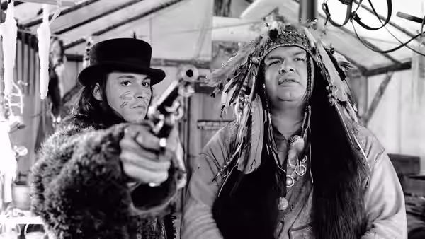 William Blake (Johnny Depp) aims a revolver while Nobody (Gary Farmer) watches
