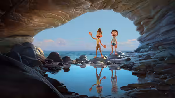 Alberto and Luca stand in a rocky seaside cave above a reflective pool