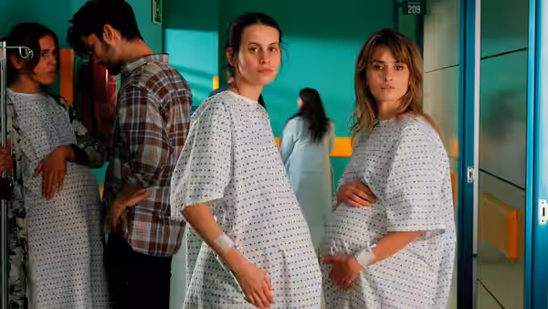 Pregnant Janis (Penélope Cruz) and Ana (Milena Smit) stand in hospital gowns in a corridor