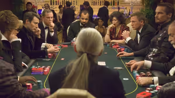 James Bond (Daniel Craig) seated at a green felt poker table with players