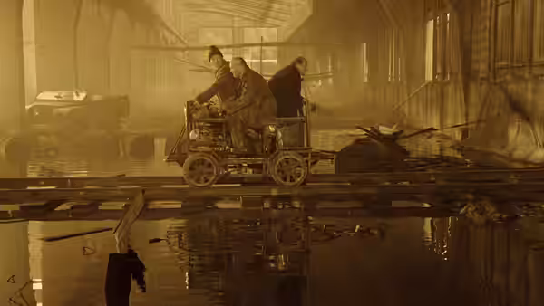 Three men ride a rail trolley through a flooded industrial workshop