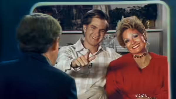 Tammy Faye Bakker (Jessica Chastain) and Jim Bakker (Andrew Garfield) address an interviewer on television