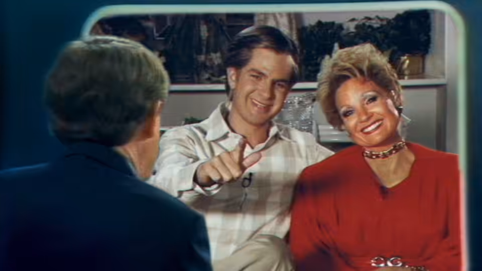 Tammy Faye Bakker (Jessica Chastain) and Jim Bakker (Andrew Garfield) address an interviewer on television