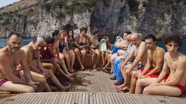 Fabietto Schisa (Filippo Scotti) sits with family on a boat by rocky cliffs