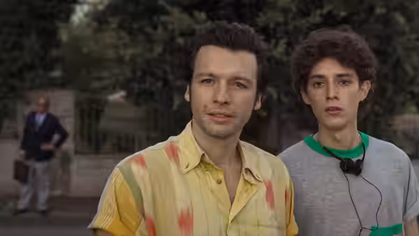 Fabietto Schisa and a man in a yellow shirt stand together in a garden