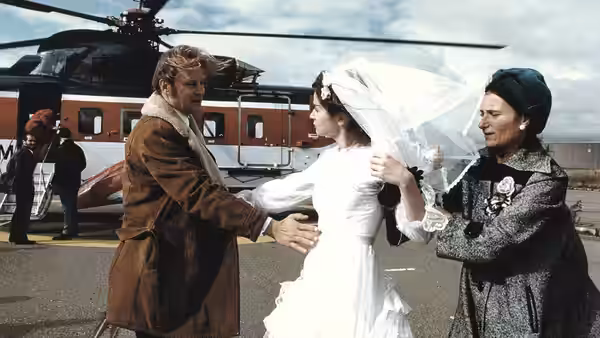 Jan (Stellan Skarsgård) embracing Bess (Emily Watson) in her wedding dress by a helicopter