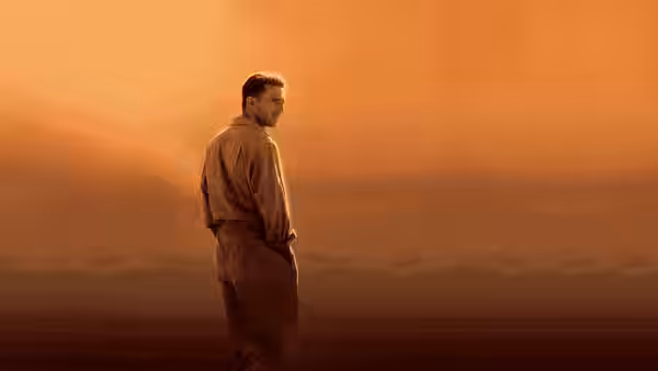 Almásy (Ralph Fiennes) stands alone in a vast empty desert at dusk