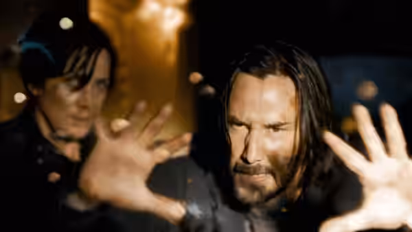 Neo raises his hands as a dark-haired man behind him reaches forward