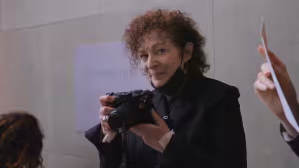 Nan Goldin holds a camera inside a gallery