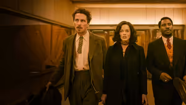 Burt Berendsen (Christian Bale), Valerie Voze (Margot Robbie), and Harold Woodman (John David Washington) walk through a hallway