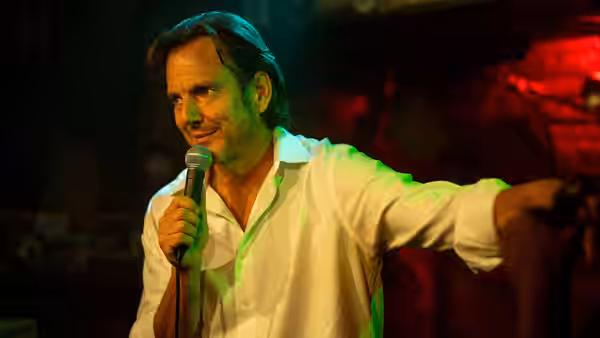 Alex Novak (Will Arnett) performing on stage with a microphone in hand